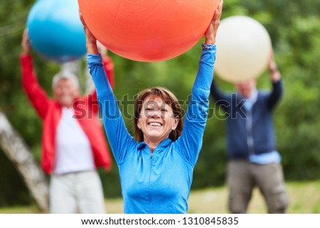 Active senior woman exercises fitness with gym ball in a rehab class