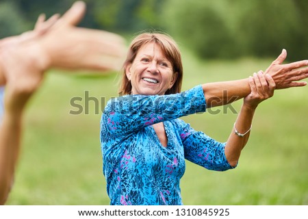 Vital senior woman does a healthy stretching exercise for the upper arms in the rehab