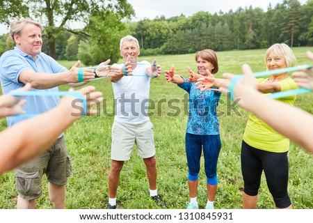 Group of active seniors exercises with the gym band in a rehab class