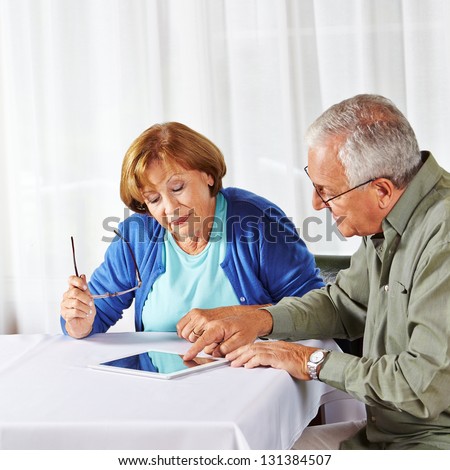 Senior man showing old woman in nursing home a tablet computer