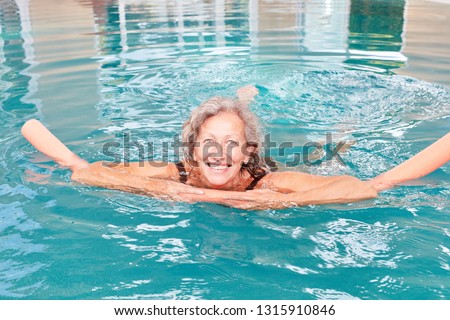 Happy senior woman with swimming aid at aquafitness and hydrotherapy