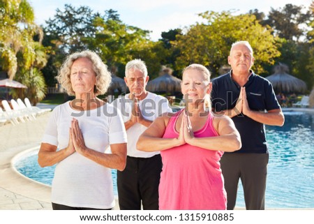 Seniors doing a wellness yoga exercise by the pool and folding their hands