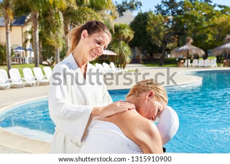 Physiotherapist gives senior woman a massage at the wellness hotel by the pool