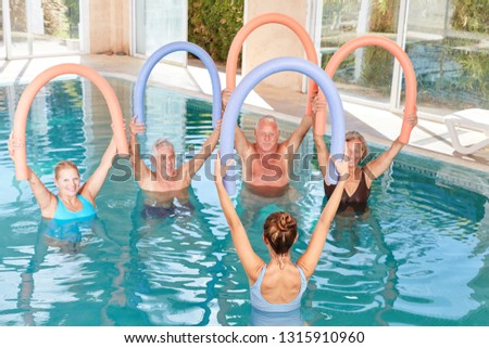 Senior group is doing aqua gym with swimming noodle in the swimming pool