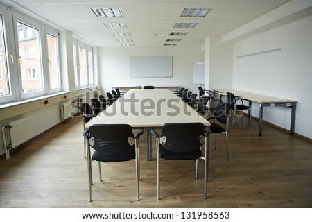 Empty clean conference room with whiteboard and tables and chairs