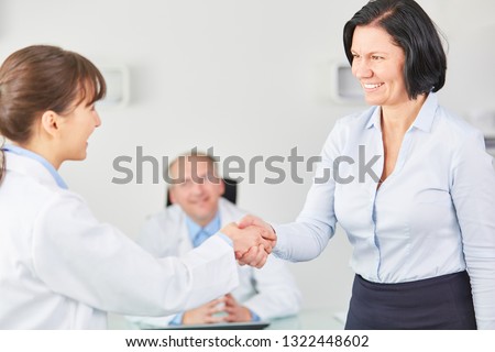 Woman as senior doctor share handshake with intern in clinic