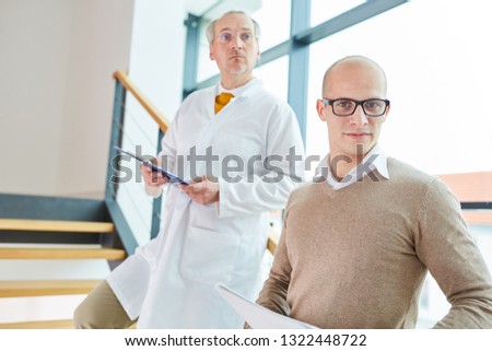 Young man as doctor with chief physician at hospital