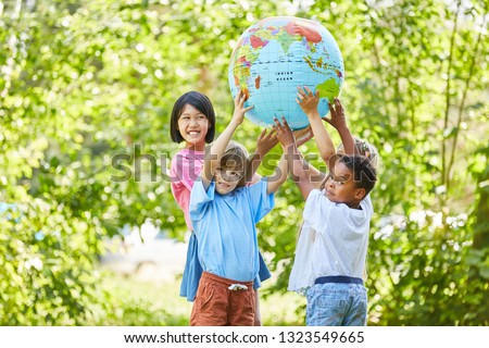 International children group as a team holds a globe in nature