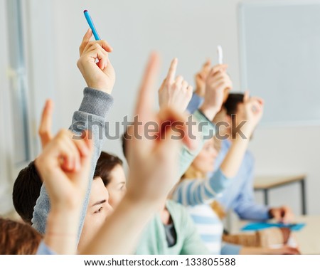 Many Students Raising Their Hands In Class For An Answer