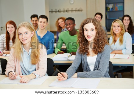 Many happy students sitting in university course classroom