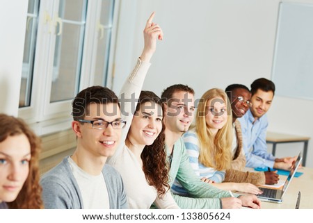Young smiling woman raising her hand in a university class