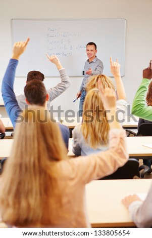 Students answering question in school class with teacher on whiteboard