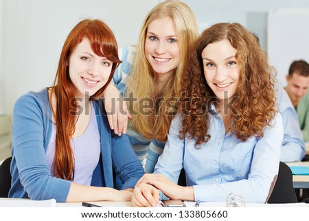 Three young happy attractive women in university class