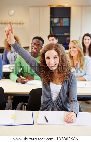 Diligent smiling student raising her hand in a school class