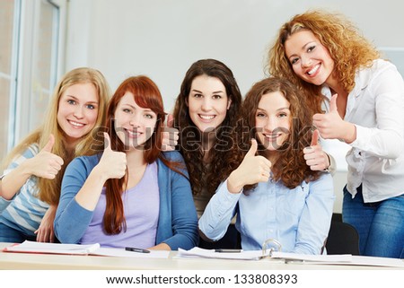 Happy successful women holding thumbs up in a university class