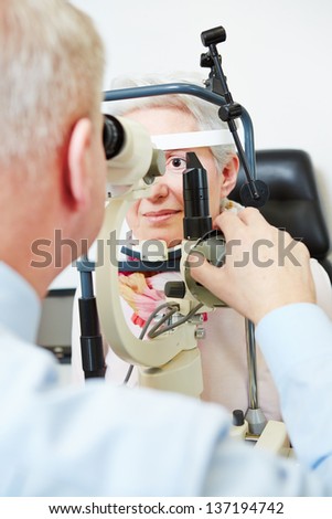 Ophthalmologist using slit lamp to check eye of senior woman