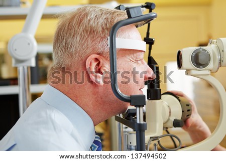 Senior man at eye measurement at ophthalmologist with slit lamp
