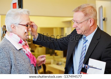 Elderly happy woman buying new glasses at optician store
