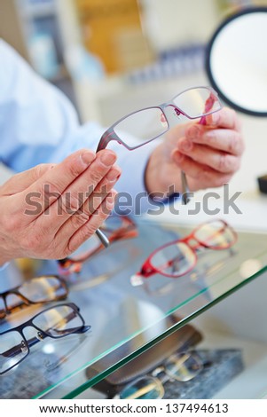 hands of an optician offering new glasses in his retail store