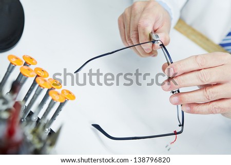 Hand of optician fixing metall jaws of glasses with pliers