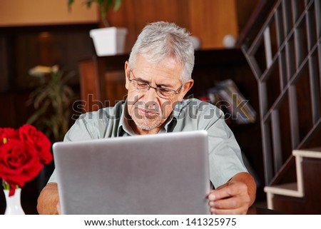 Senior man in hotel lobby using a tablet computer