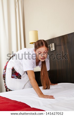 Cleaning lady in hotel making bed during housekeeping