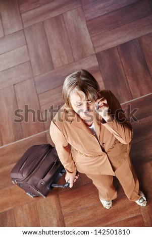 Old woman traveling with luggage talking on the phone