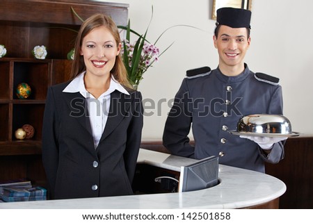 Happy Concierge And Receptionist In Hotel Waiting At Counter