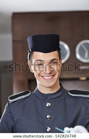 Happy hotel concierge smiling with key card in his hand