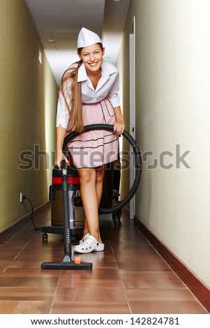 Hotel maid working with vacuum cleaner in a corridor