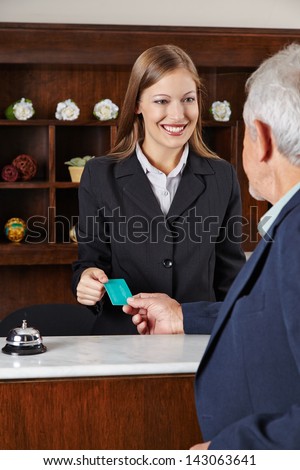 Smiling female receptionist in hotel greeting a senior man