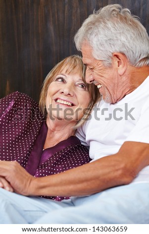 Happy senior couple having fun in bed in a hotel room