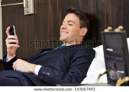 Successful businessman checking smartphone in his hotel room