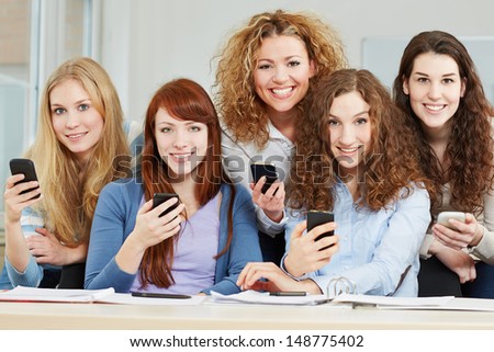 Young attractive women with different smartphones in university class