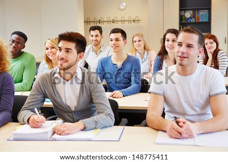 Many students in seminar studying and listening in university classroom