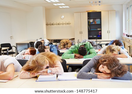 Many tired students sleeping in classroom with their heads on the table