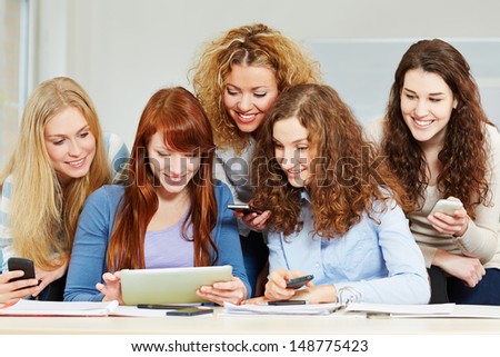 Happy women learning with tablet computer and smartphones in university class