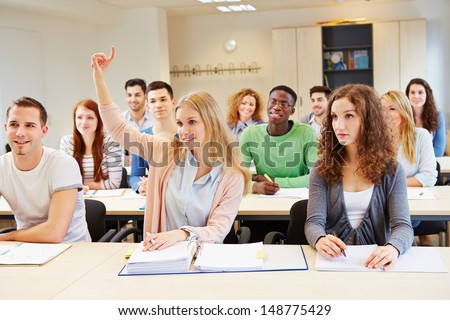 Diligent female student lifting hand in university seminar classroom