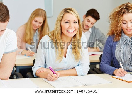 Happy students taking notes in class of a university