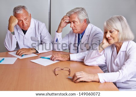 Three worried doctors thinking in a team meeting