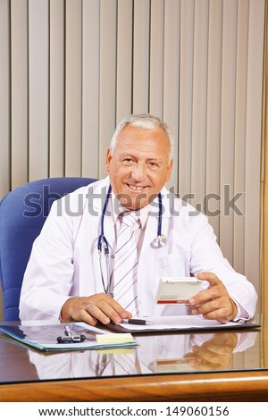 Smiling doctor prescribing medication in his office