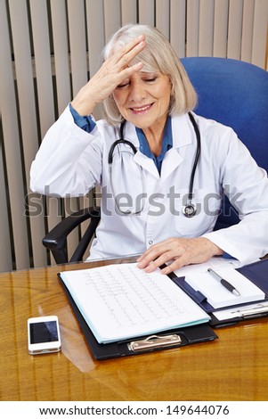 Elderly doctor in office has an idea and slaps his head