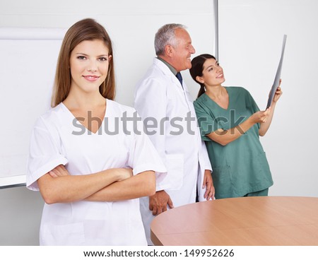 Young happy nurse with her arms crossed in a team in a hospital
