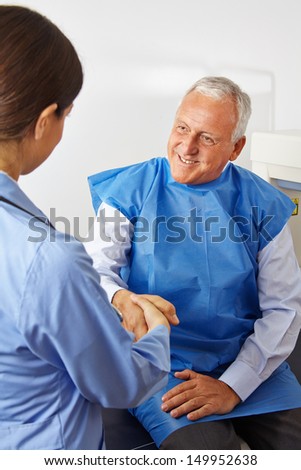 Senior patient in radiology shaking hand of doctor in a hospital