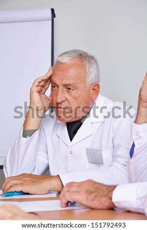 Pensive senior doctor thinking in a team meeting