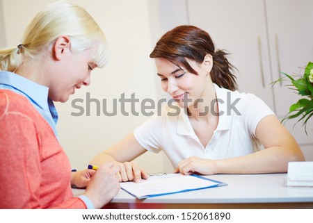 Female patient at doctor filling out and signing forms