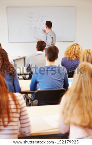 Teacher writing financial mathematics formulas on whiteboard in university
