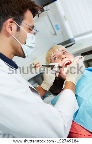Female patient for preventive medical checkup at dentist with probe and mirror