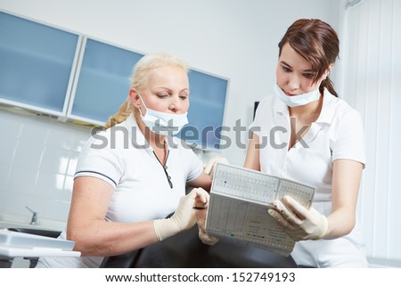 Dentist and dental assistant reading medical records of a patient prior to treatment