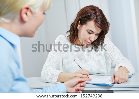 Female patient at reception of doctors office filling out medical form